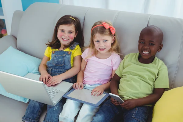 Щасливі діти сидять разом з планшетом, ноутбуком і телефоном — стокове фото