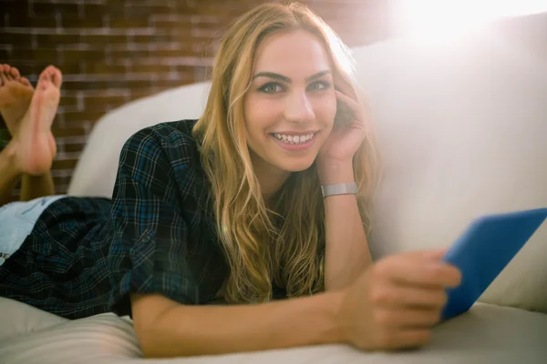 Hezká blondýnka relaxační na gauči pomocí tabletu — Stock fotografie