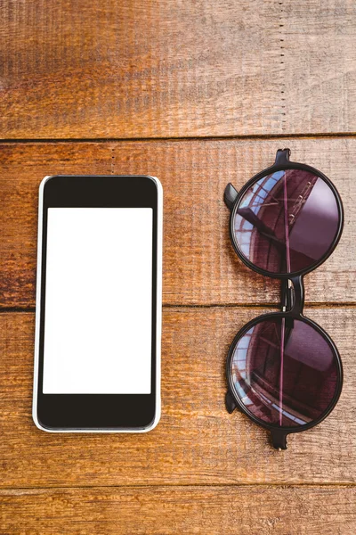 Brýle a smartphone na dřevěný stůl — Stock fotografie