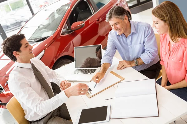 Clientes assinando documentos no showroom do carro — Fotografia de Stock