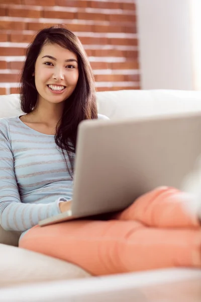 Азіатський жінка на дивані, використовуючи ноутбук — стокове фото