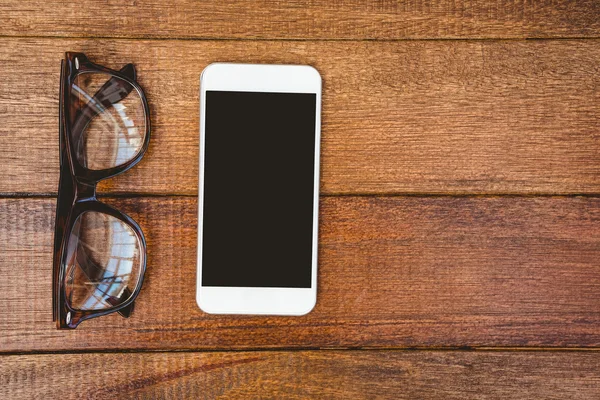 Brille und Smartphone auf Holztisch — Stockfoto