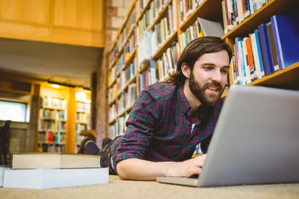 Étudiant utilisant un ordinateur portable sur le sol dans la bibliothèque — Photo