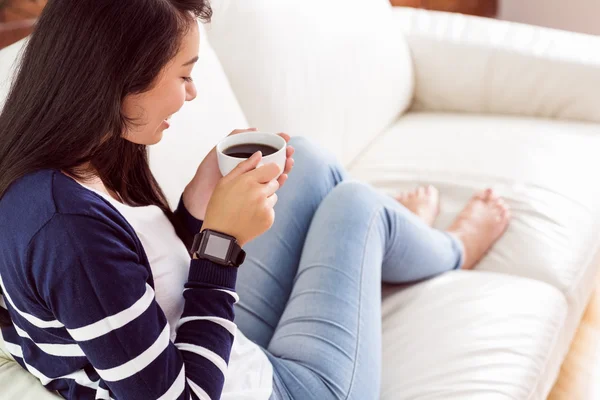 Asiatin entspannt sich auf Couch mit Kaffee — Stockfoto