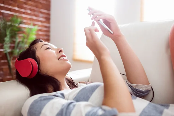 Sorrindo mulher asiática no sofá ouvindo música — Fotografia de Stock