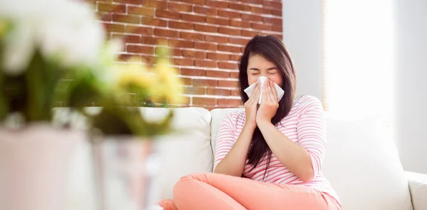 Asian woman blowing her nose on couch — Stock Photo, Image