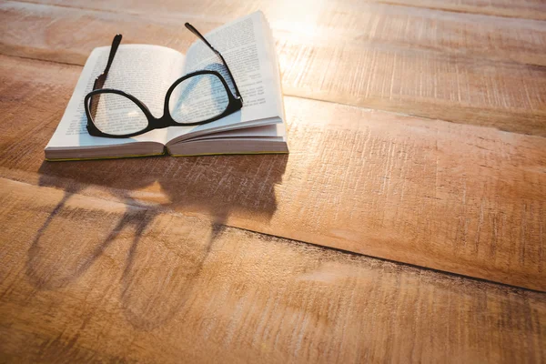 Kniha a brýle na dřevěný stůl — Stock fotografie