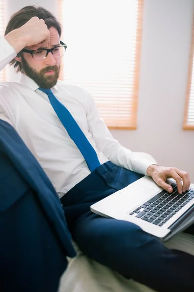 Businessman using laptop on the couch — Stock Photo, Image