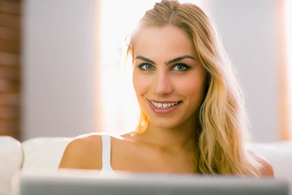 Ładna blondynka za pomocą laptopa na kanapie — Zdjęcie stockowe