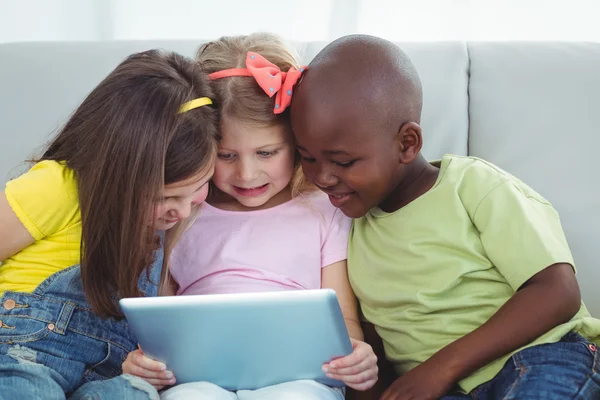 Bambini felici seduti insieme con una tavoletta — Foto Stock