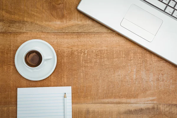 Laptop en een kopje koffie op houten bureau — Stockfoto