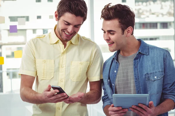 Sonriente equipo creativo de pie en una línea utilizando la tecnología —  Fotos de Stock