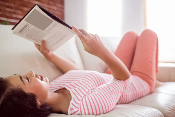 Smiling asian woman on couch reading — Stock Photo, Image