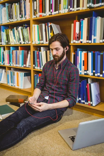 Student using phone in library on floor — Stock Photo, Image
