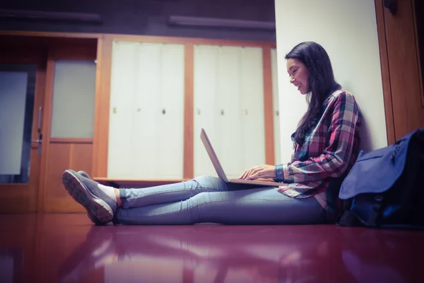 Uśmiechający się student siedząc na podłodze i przy użyciu laptopa — Zdjęcie stockowe