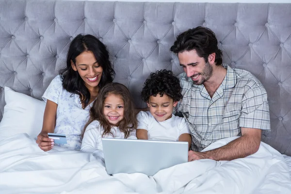Lycklig familj med laptop på sängen — Stockfoto