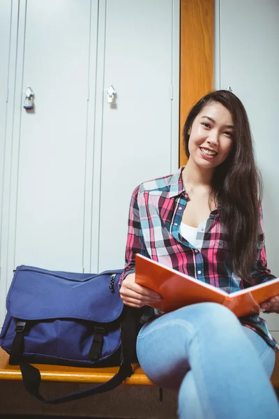 Estudante sorrindo sentado e lendo um caderno — Fotografia de Stock