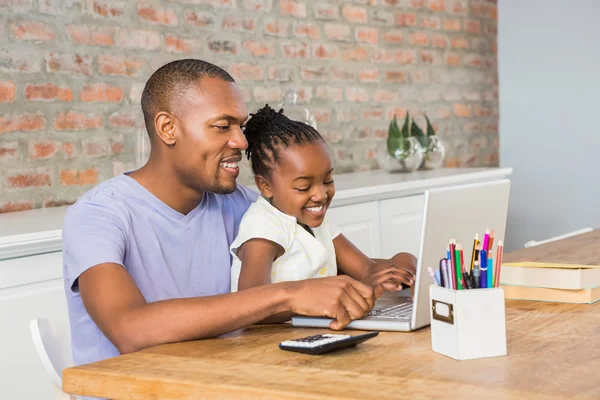 Мила дочка використовує ноутбук за столом з батьком — стокове фото