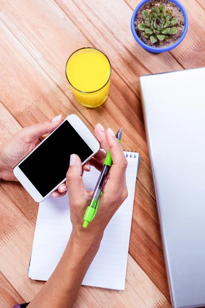 Sobrecarga de manos femeninas sosteniendo el teléfono inteligente y tomando notas —  Fotos de Stock