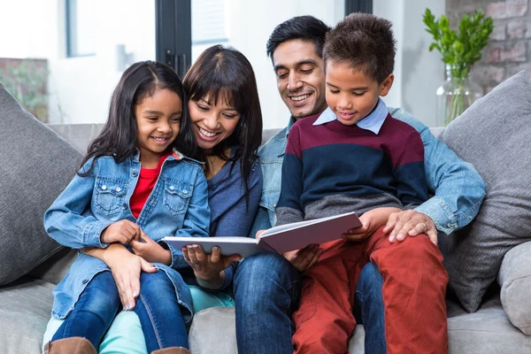 Happy young family reading a book together — Stock Photo, Image