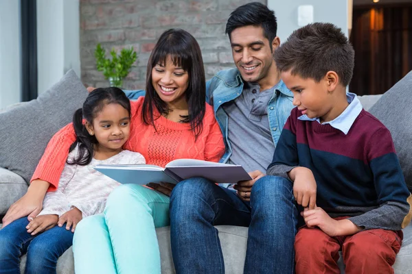 Familia joven y feliz leyendo un libro juntos — Foto de Stock