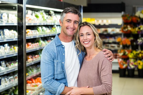 Lächelndes Paar umarmt sich im Fruchtgang — Stockfoto