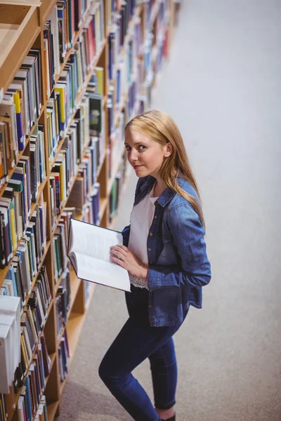 Standing student reading book in library — Stock Photo, Image