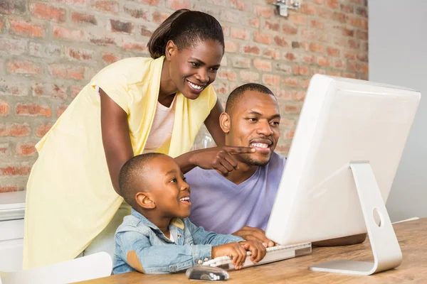 Casual lachende familie op een computer — Stockfoto