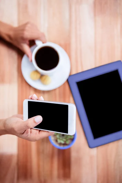 Overhead de mãos femininas segurando smartphone e café — Fotografia de Stock