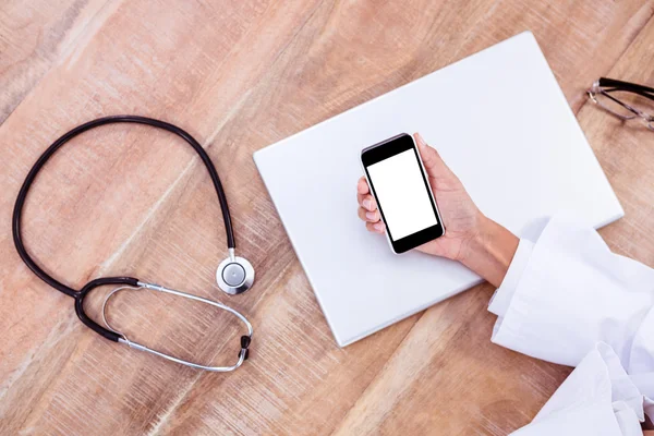 Médecin utilisant smartphone sur bureau en bois — Photo