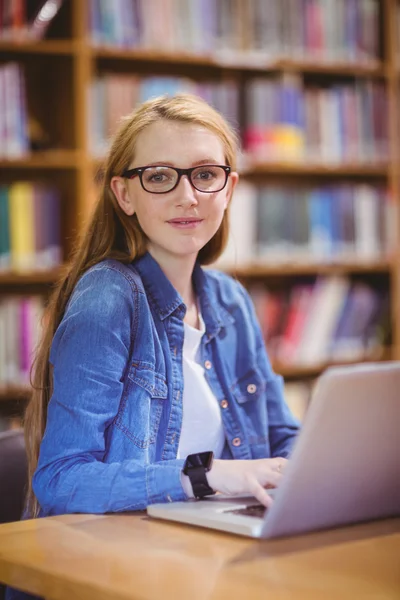 Student z pokładzie smartwatch korzysta z laptopa w bibliotece — Zdjęcie stockowe