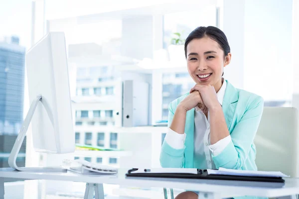 Lächelnde Geschäftsfrau mit Zetteln am Schreibtisch — Stockfoto