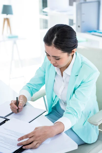 Mujer de negocios sonriente escribiendo en un bloc de notas —  Fotos de Stock