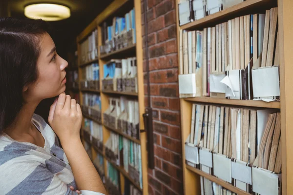 Pretty student looking at bookshelves — Stock Photo, Image