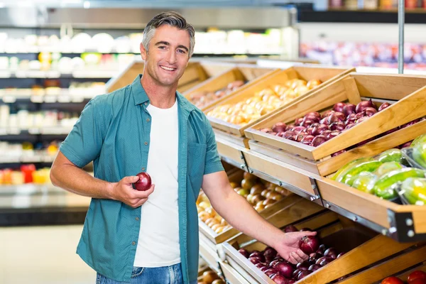 Hombre sonriente eligiendo una cebolla —  Fotos de Stock