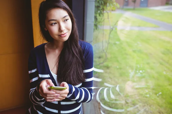 Étudiant souriant avec smartphone et regardant par la fenêtre — Photo