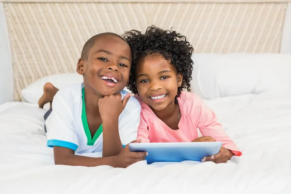 Fratelli felici utilizzando tablet sul letto — Foto Stock