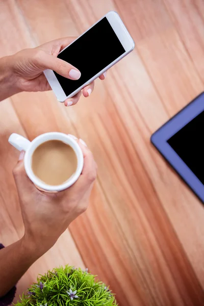 Sobrecarga de manos femeninas sosteniendo el teléfono inteligente y el café —  Fotos de Stock