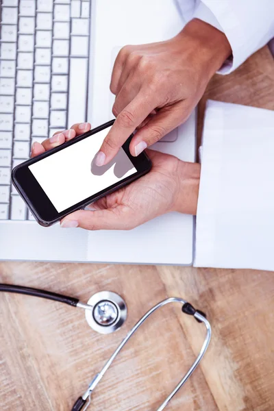 Doctor using smartphone on wooden desk — Stock Photo, Image