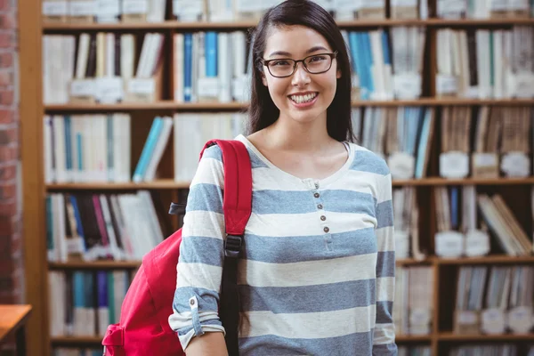 Estudiante sonriente con mochila de pie en la biblioteca — Foto de Stock