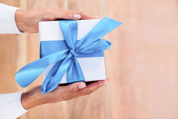 Woman presenting gift with blue ribbon — Stock Photo, Image