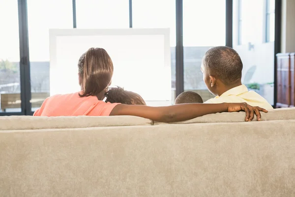 Через плечо взгляд случайной семьи, смотрящей телевизор — стоковое фото