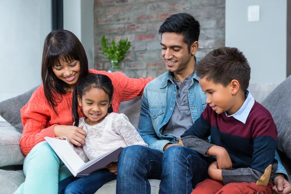 Glad ung familj läser en bok tillsammans — Stockfoto