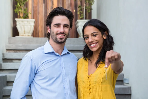 Casal feliz na frente da nova casa mostrando chaves — Fotografia de Stock