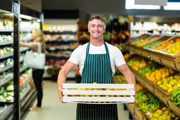 Trabalhador sorrindo transportando caixa de legumes — Fotografia de Stock