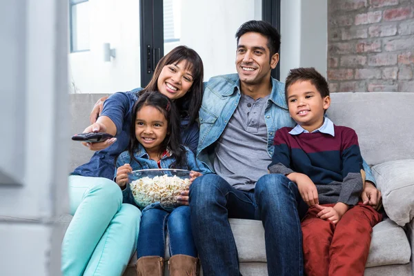 Glad ung familj äta popcorn medan du tittar på tv — Stockfoto