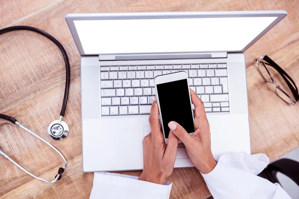 Médecin utilisant smartphone sur bureau en bois — Photo