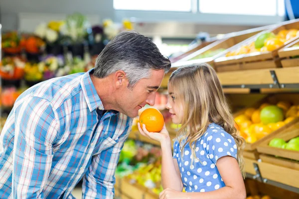 Leuk meisje een sinaasappel te houden aan haar vader — Stockfoto