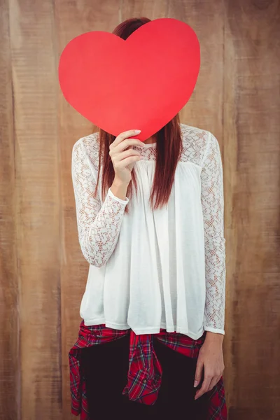 Mujer hipster sonriente detrás de un gran corazón rojo — Foto de Stock