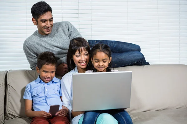 Uśmiechający się rodzina korzysta z laptopa na kanapie — Zdjęcie stockowe